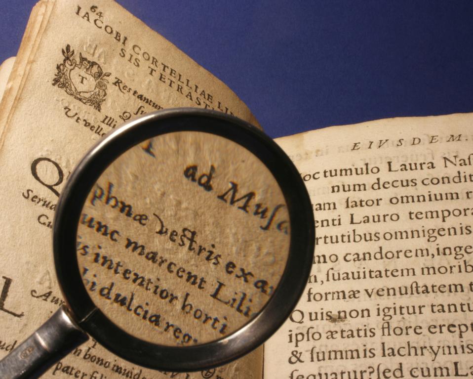 Imagen de una lupa sobre un libro antiguo con texto en color